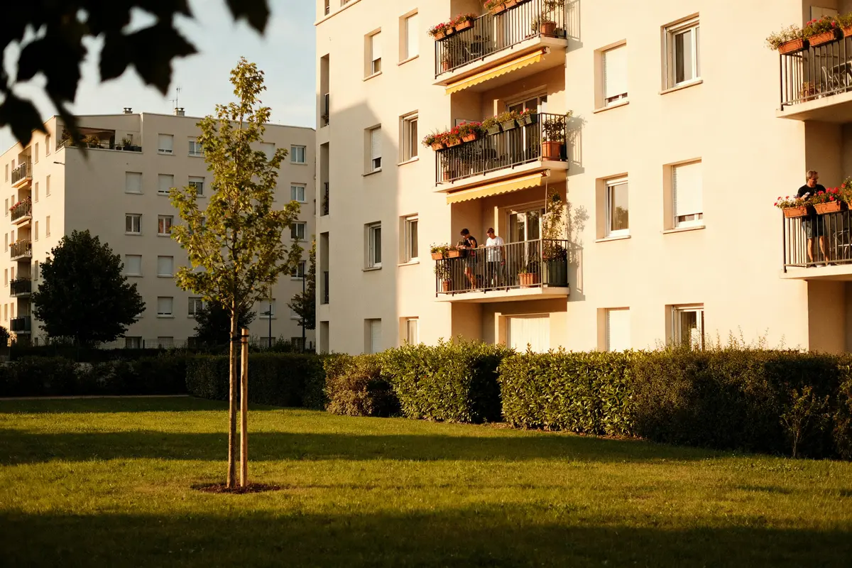 Bâtiments résidentiels avec balcons fleuris et un arbre, ambiance floriane paisible ensoleillée